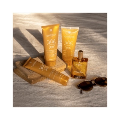 Produtos de beleza RENÉ FURTERER em tubos e frasco dourado junto a óculos de sol sobre superfície clara