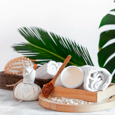 Produtos de spa com toalha branca e folhas verdes ao fundo