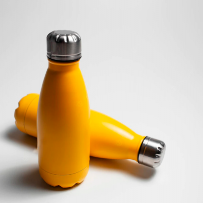 Garrafa térmica amarela com tampa prateada sobre superfície branca