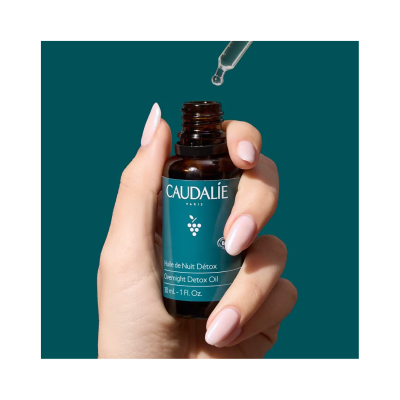 Frasco de óleo detox noturno Caudalie segurado por mão com conta-gotas