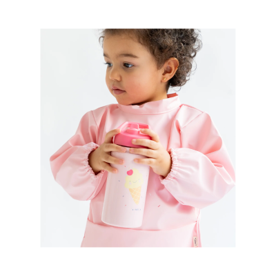 Criança com avental rosa a segurar copo térmico rosa com desenho de gelado.