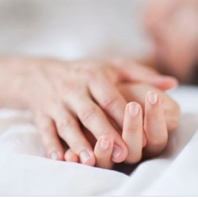 Duas mãos adultas entrelaçadas sobre tecido branco