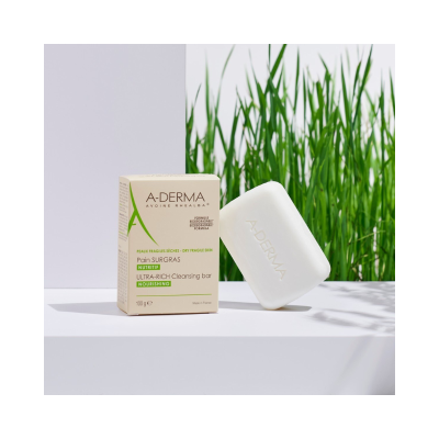 Sabonete sólido A-DERMA e embalagem bege com texto sobre pele seca e frágil junto a plantas verdes