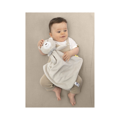 Bebé com brinquedo de peluche em superfície bege tricotada