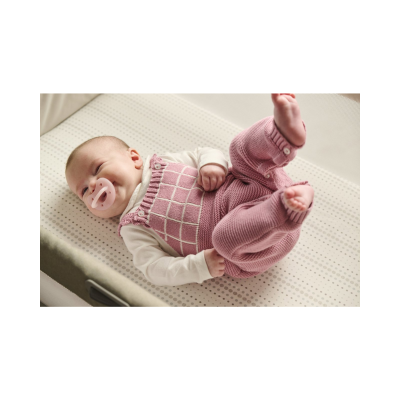 Bebé deitado com macacão rosa e chucha cor-de-rosa