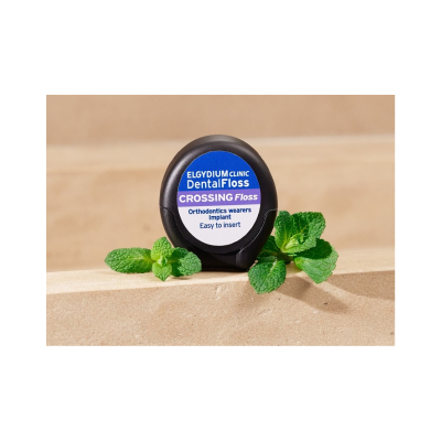 Fio dental ELGYDIUM CLINIC Dental Floss num estojo preto com folhas de hortelã