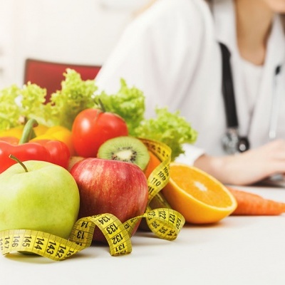 Fruta variada com fita métrica e copo de sumo de laranja em ambiente clínico