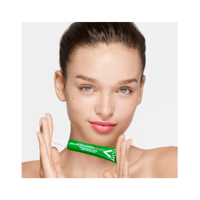 Produto tubo verde com texto branco 'MAMADERM ALOE' sendo segurado por mulher com pele clara