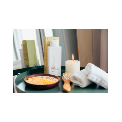 Conjunto de champô DAveia, vela acesa, escova de madeira, toalhas brancas e prato com sumos e cereais sobre bandeja verde