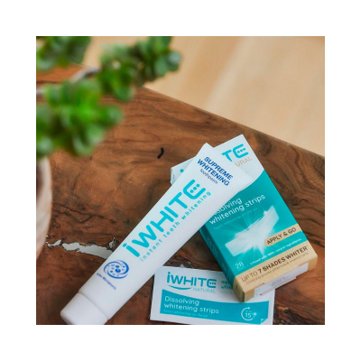 Produtos iWhite para branqueamento dos dentes sobre uma mesa de madeira.