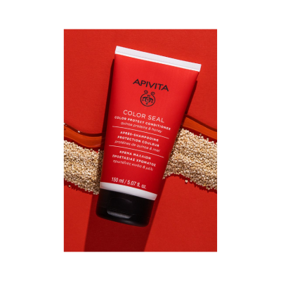 Condicionador Apivita Color Seal vermelho com tampa preta em fundo vermelho com quinoa