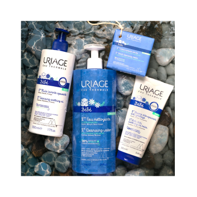 Produtos bebé URIAGE Eau Thermale em embalagens azul e branco sobre pedras azuis e brancas