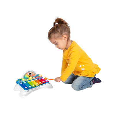 Menina a brincar com xilofone colorido de brinquedo no chão