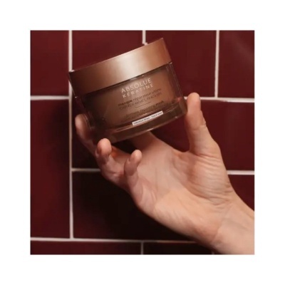 Frasco castanho de creme L'Oréal Paris ABSOLUE PEPTIDE GLOW segurado por uma mão