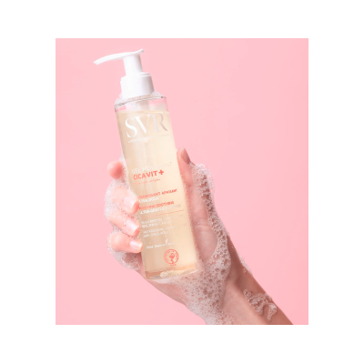 Mão ensaboada a segurar gel SVR CICA VIT+ com doseador em fundo cor-de-rosa