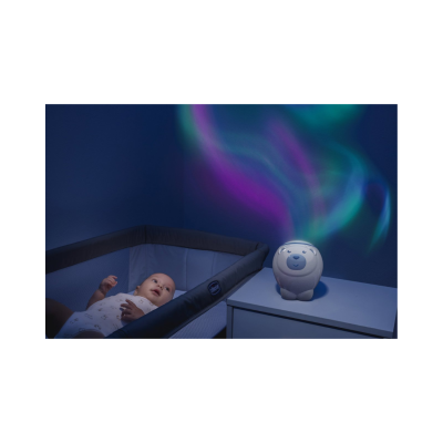 Luz noturna de urso projetando luzes coloridas junto a berço com bebé e parede azul