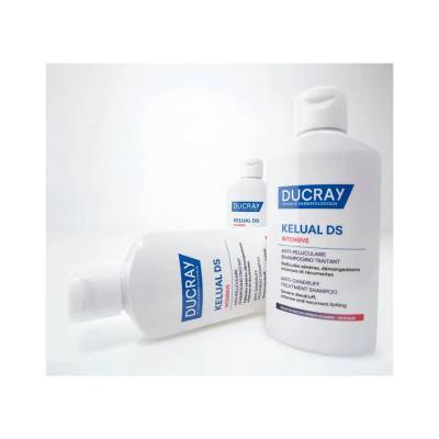 Três frascos brancos de champô Ducray Kelual DS Intensive com rótulos azuis e vermelhos