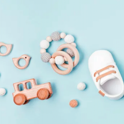Sapatinhos de bebé brancos com atacadores cor de laranja junto a brinquedos de madeira e contas de croché