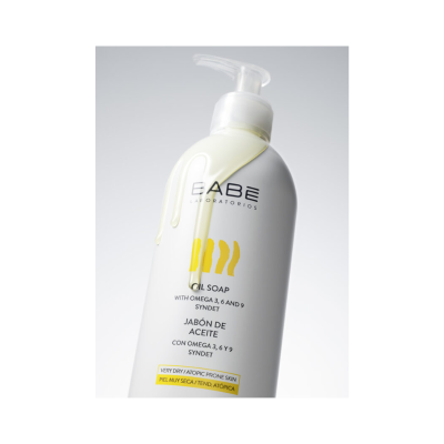 Frasco de sabonete líquido Babé Laboratorios branco com doseador, texto em inglês e espanhol, óleo escorrendo na embalagem.