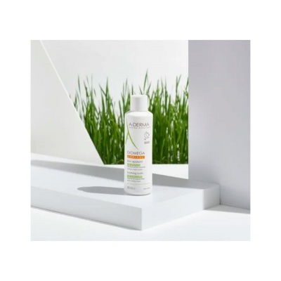 Frasco branco de A-DERMA Exomega Control em fundo branco com relva