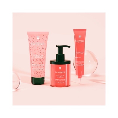 Produtos cosméticos René Furterer Tonucia em embalagens rosa e vermelha sobre fundo rosa