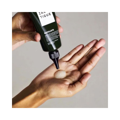 Frasco verde com esfoliante a ser aplicado na mão