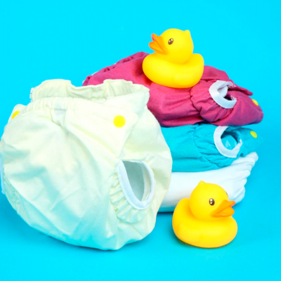 Fraldas reutilizáveis coloridas e patinhos de borracha amarelos sobre fundo azul