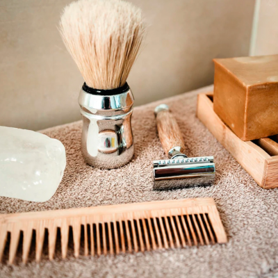 Conjunto de barbear com pincel, pente, lâmina, sabão e bloco de cristal sobre toalha