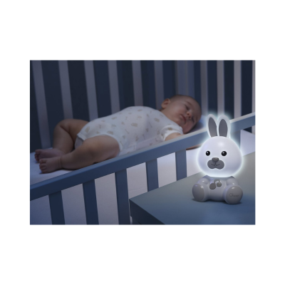 Bebé a dormir num berço azul com um candeeiro de presença coelho iluminado numa mesa