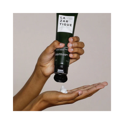 Mãos a aplicar creme branco de tubo verde LAZARTIGUE