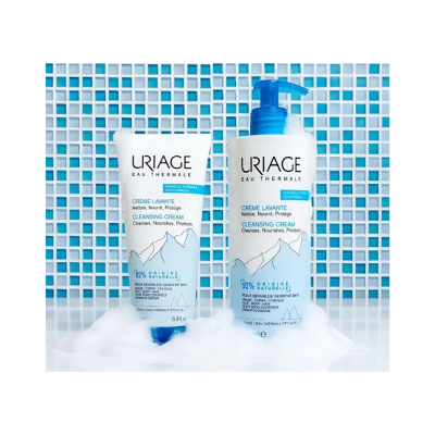 Frascos de creme de limpeza Uriage sobre fundo de azulejos azuis com espuma