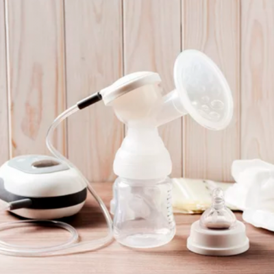 Bomba tira-leite elétrica branca com acessórios sobre superfície de madeira.