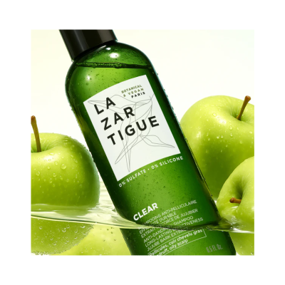 Frasco verde de shampoo LAZARTIGUE com etiqueta branca e maçãs verdes molhadas