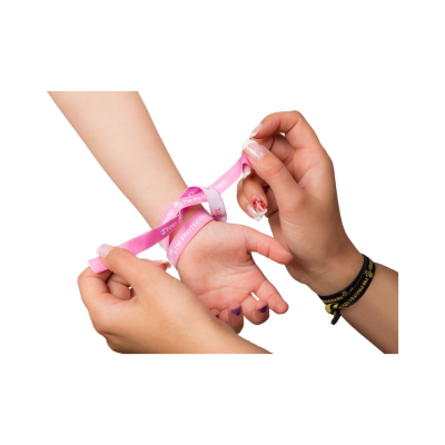 Pulseira rosa de tecido com texto sendo amarrada no pulso de uma criança