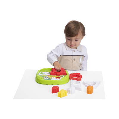 Criança a brincar com brinquedo educativo de formas coloridas em mesa branca