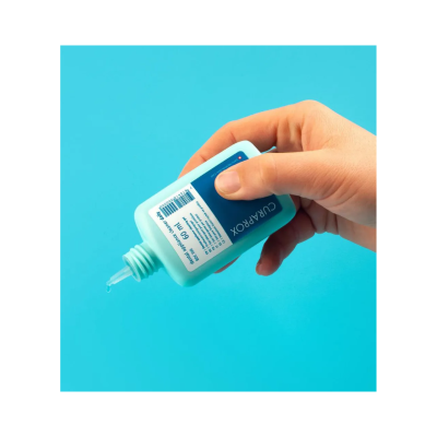 Frasco azul claro de gel clear segurado por mão com fundo azul