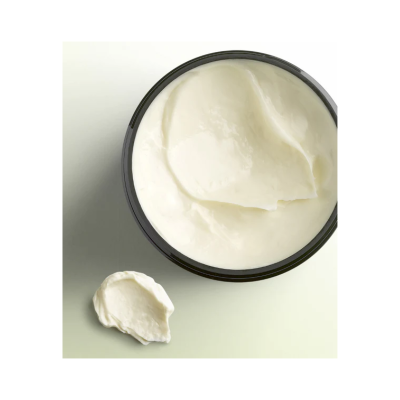 Recipiente preto redondo com creme branco cremoso e porção de creme na superfície ao lado