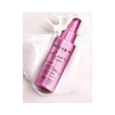 Frasco de spray NUXE hair prodigieux LE LAIT cor de rosa metálico sobre líquido branco.