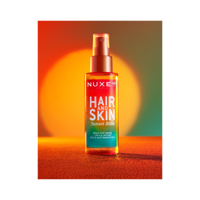 Frasco spray NUXE Hair and Skin Sunset Bliss em fundo colorido