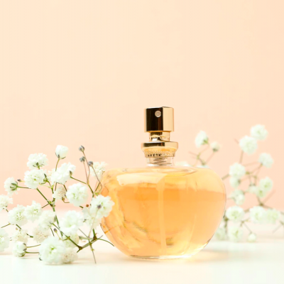 Frasco de perfume âmbar com tampa dourada rodeado por flores brancas