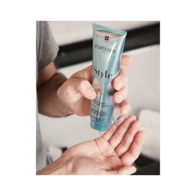 Tubo azul claro de gel de cabelo Furterer Paris em mão, gota transparente a cair na outra mão