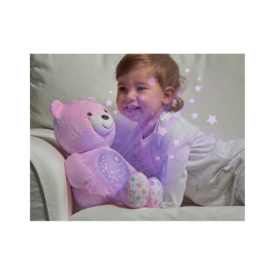 Criança com ursinho de peluche rosa num sofá bege