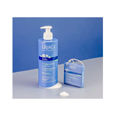 Produtos de limpeza bebé URIAGE em embalagem azul com dispenser e caixa azul sólida, sobre superfície cinzenta e fundo azul.