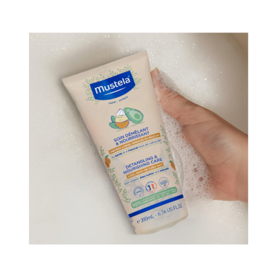 Tubo de creme Mustela 200 ml segurado por mão em espuma de banho