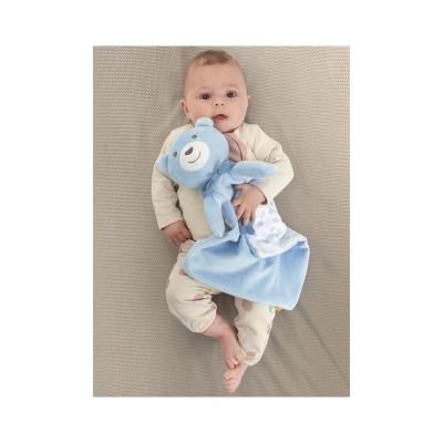 Bebé de pijama segurando cobertor de peluche azul com cabeça de urso