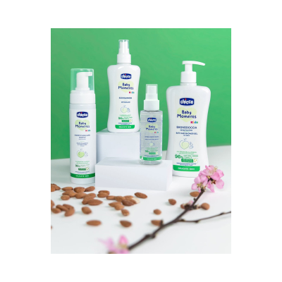 Produtos de cuidados infantis Chicco Baby Moments Kids sobre superfície branca com amêndoas e flor rosa
