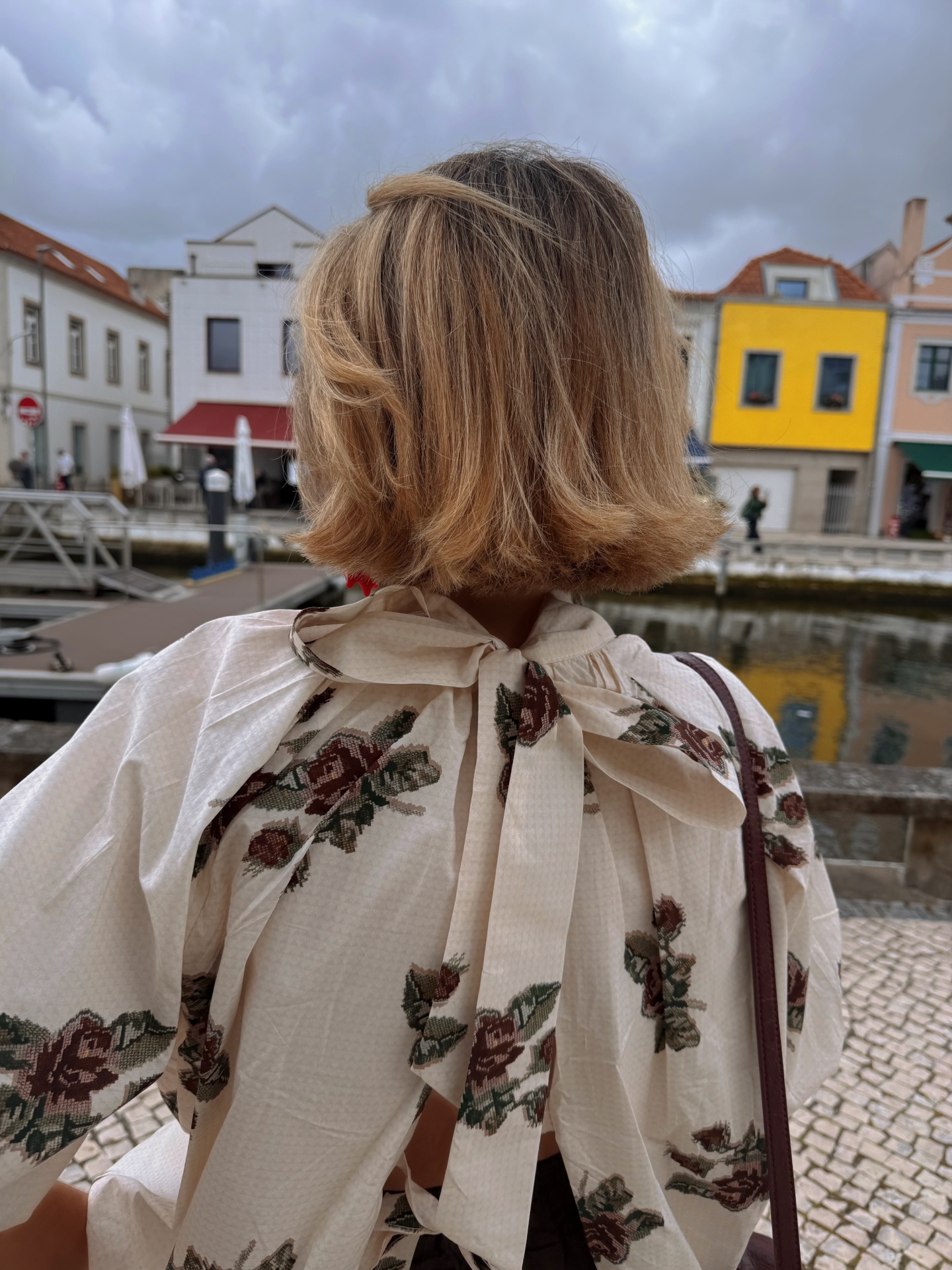 Blusa branca com padrão floral e gravata no pescoço vista de trás