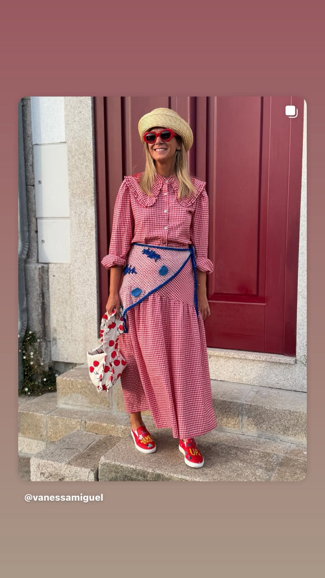 Mulher com vestido vermelho e branco, lenço azul na cintura, chapéu de palha, óculos vermelhos e ténis vermelhos