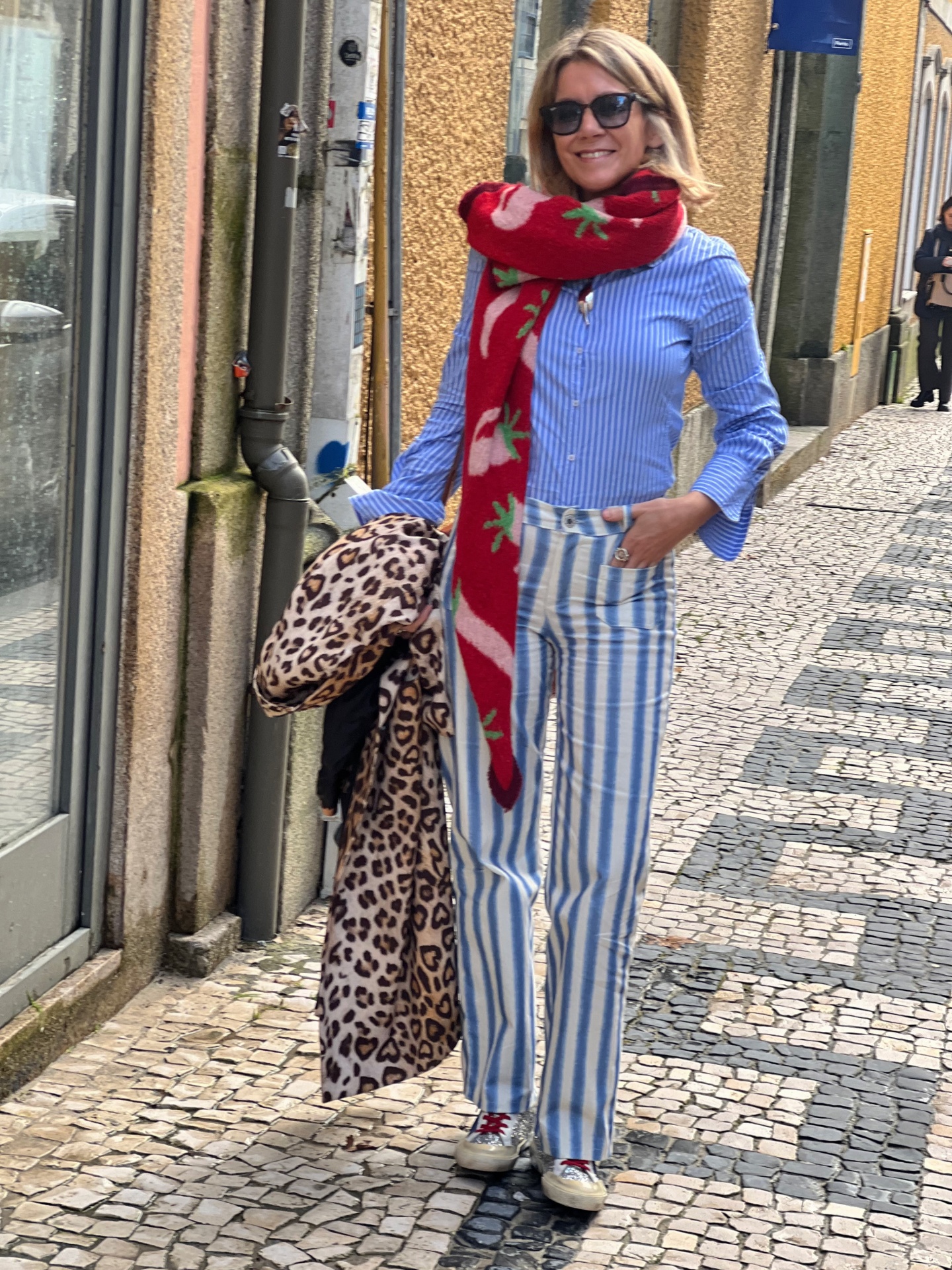 Mulher com roupa às riscas e lenço vermelho num passeio em calçada portuguesa