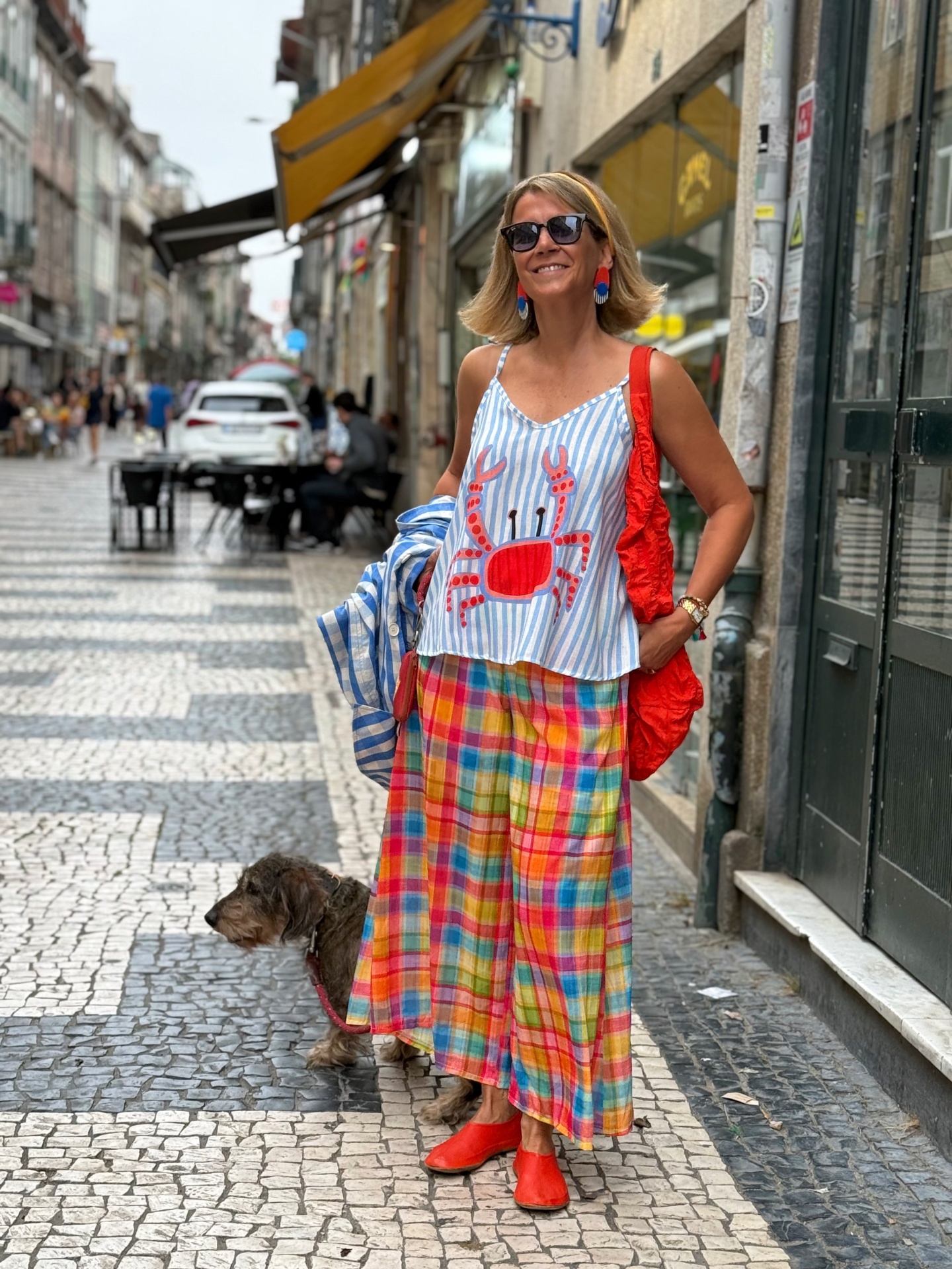 Mulher com vestido e blusa colorida numa rua com calçada portuguesa